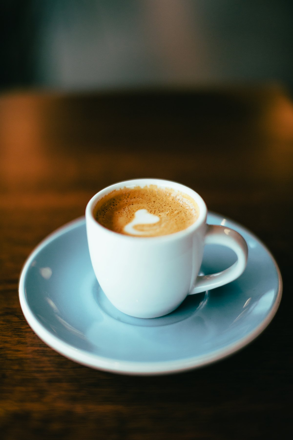 A small cup of rich espresso on a blue saucer